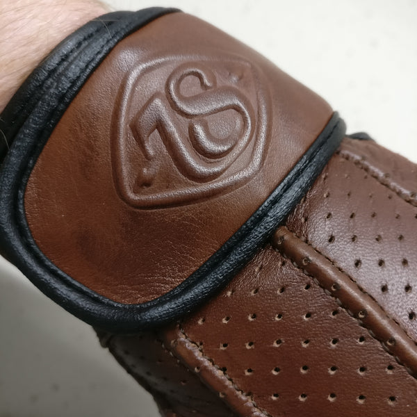 A vintage style brown leather gloves with close up on leather wrist strap showing a stylised '78' on the strap 