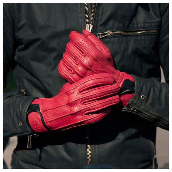 A pair of Speed motorcycle gloves by 78 Motor Co., made of red perforated leather with knuckle protection and a velcro strap on the wrist with the number '78' embossed on the strap.