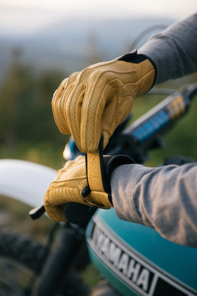 A yamaha dirt bike rider closing the wrist strap of a yellow leather vintage style motorcycle glove by 78 Motor Co