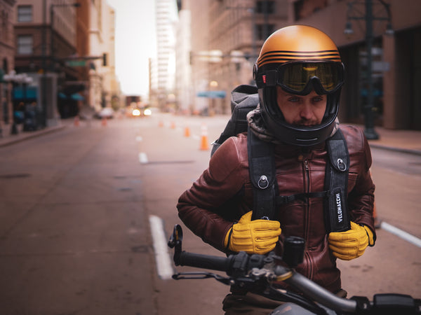 MOTORCYCLE RIDER WITH YELLOW GLOVES AND GOLD HELMET IN A CITY. 
