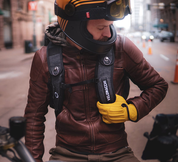 MOTORCYCLE RIDER WEARING YELLOW LEATHER MOTORCYCLE GLOVES IN AN URBAN SETTING